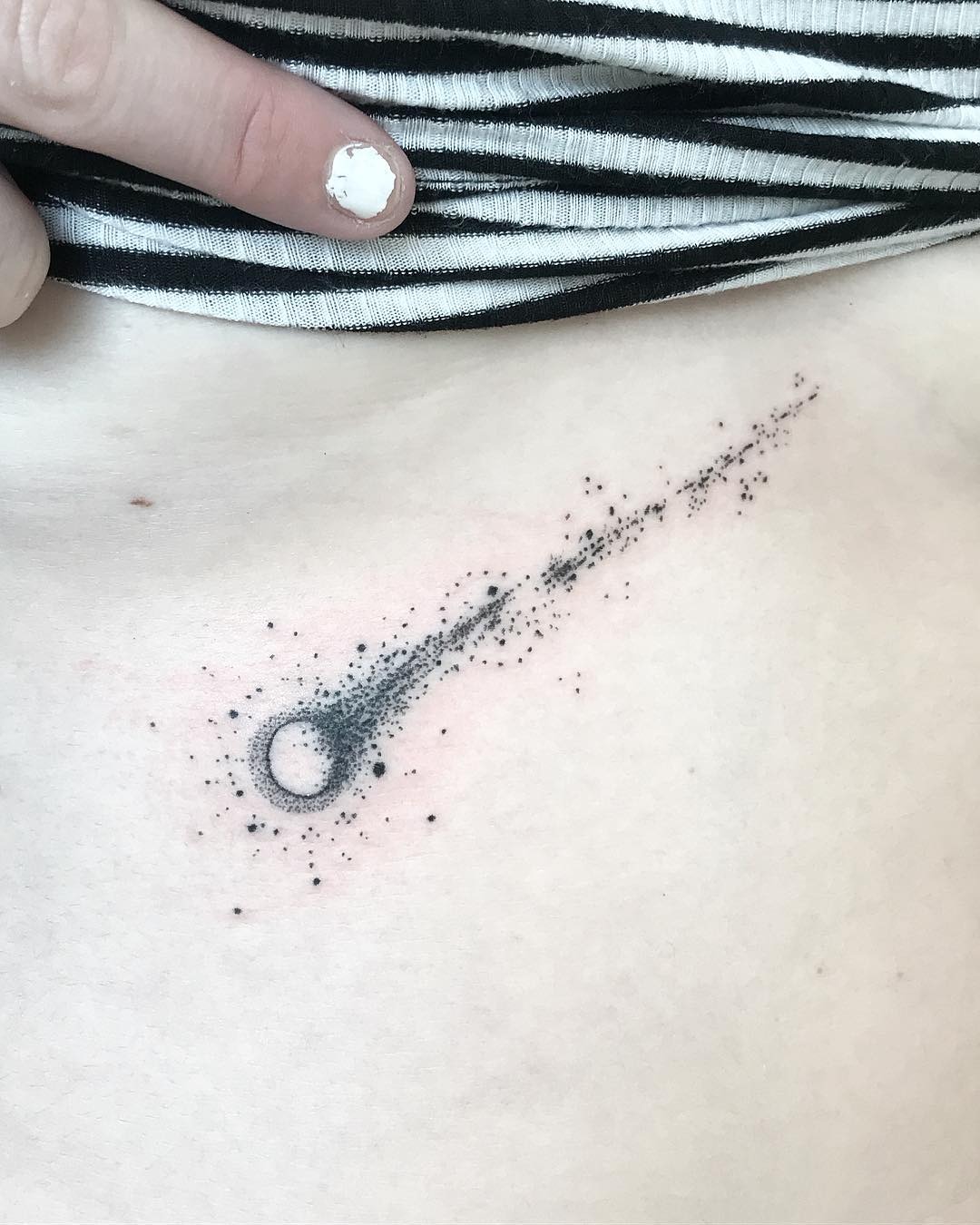 This meteor tattoo features a sleek comet design with a bright core, trailing off into an array of scattered dots.