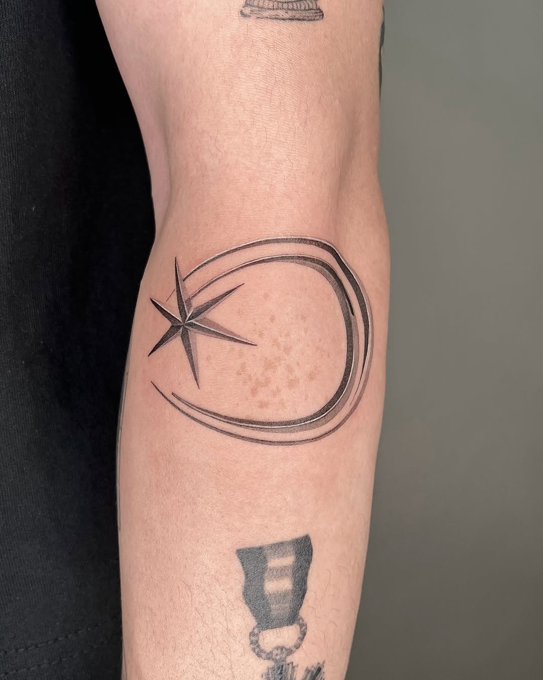 This meteor tattoo features a sleek, curved design with a shining star, highlighting the cosmic theme.