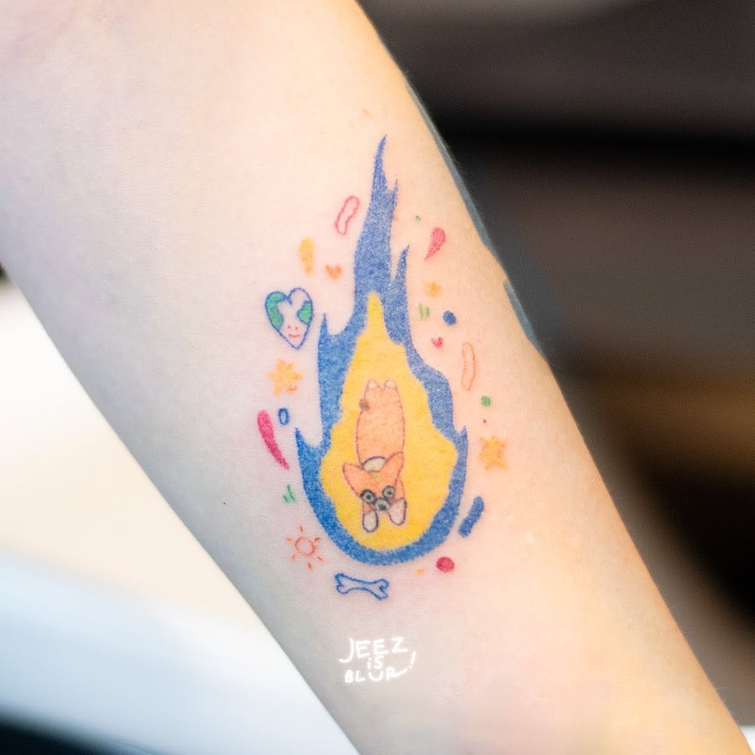 This fun tattoo features a playful design of a meteor surrounded by colorful flames.