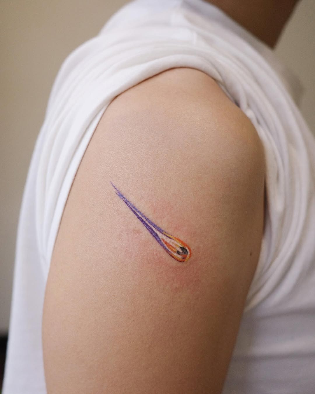 This striking meteor tattoo features a vivid color palette, with purple and orange hues radiating from a sleek tail.