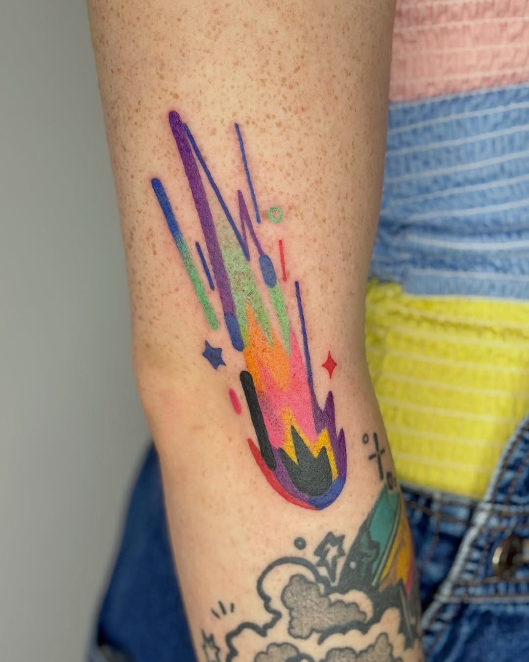 This striking meteor tattoo showcases hues of blue, pink, and orange, creating a dynamic visual effect.