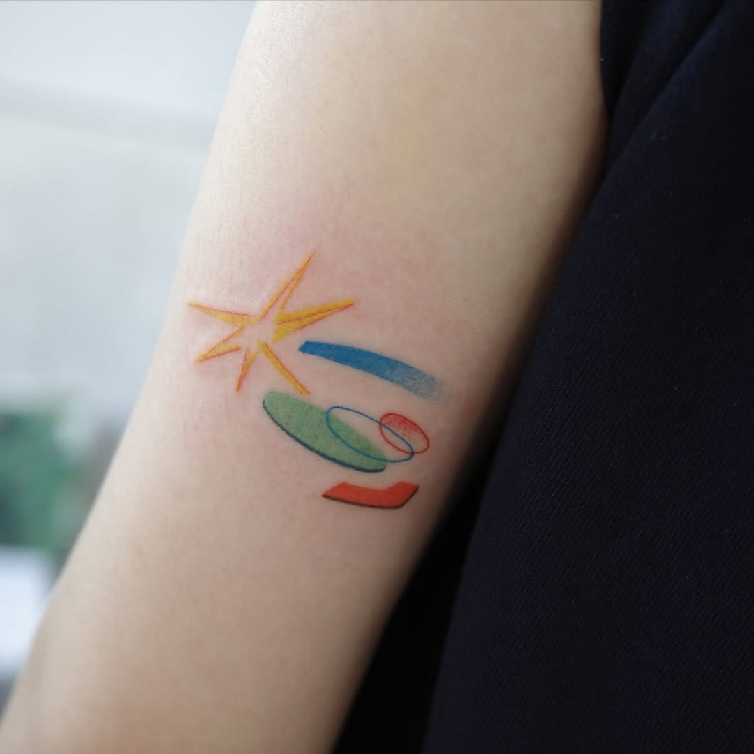 This tattoo showcases an artistic depiction of a meteor, featuring colors and playful geometric shapes.