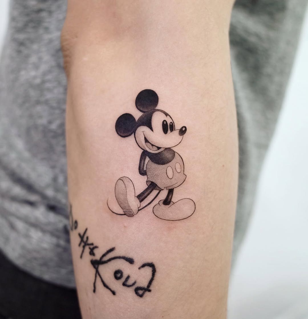 This charming Mickey Mouse tattoo showcases the beloved character in a playful pose.