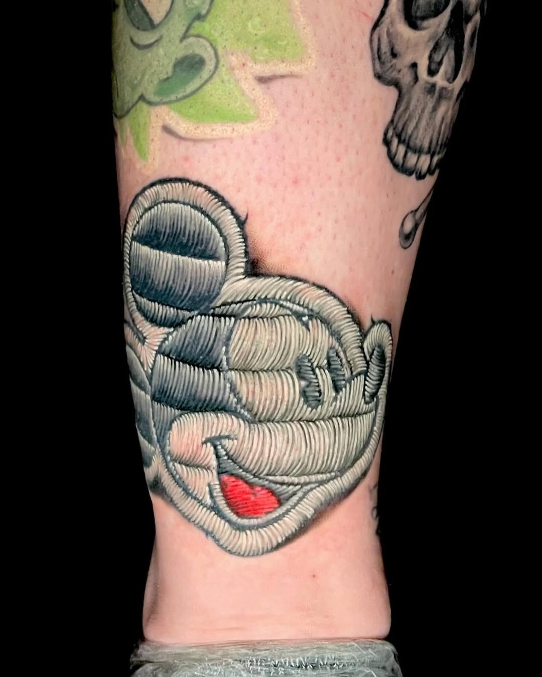 This tattoo features a playful rendition of Mickey Mouse, showing lively colors and dynamic lines.