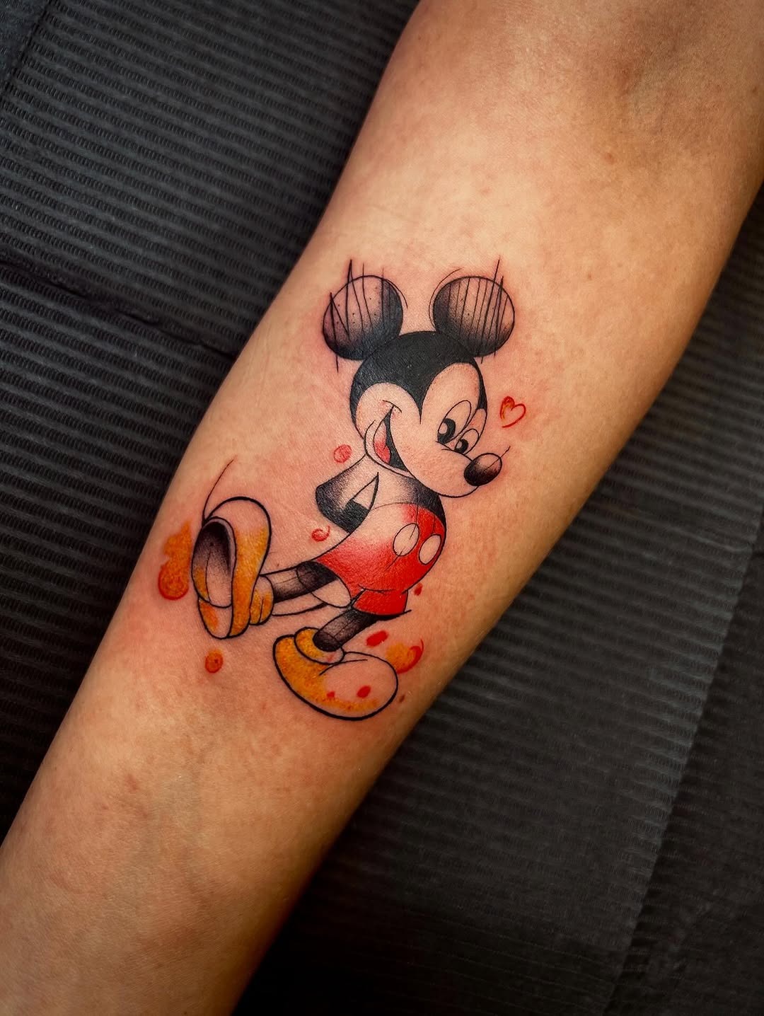 This Mickey Mouse tattoo captures the iconic character in a playful pose.