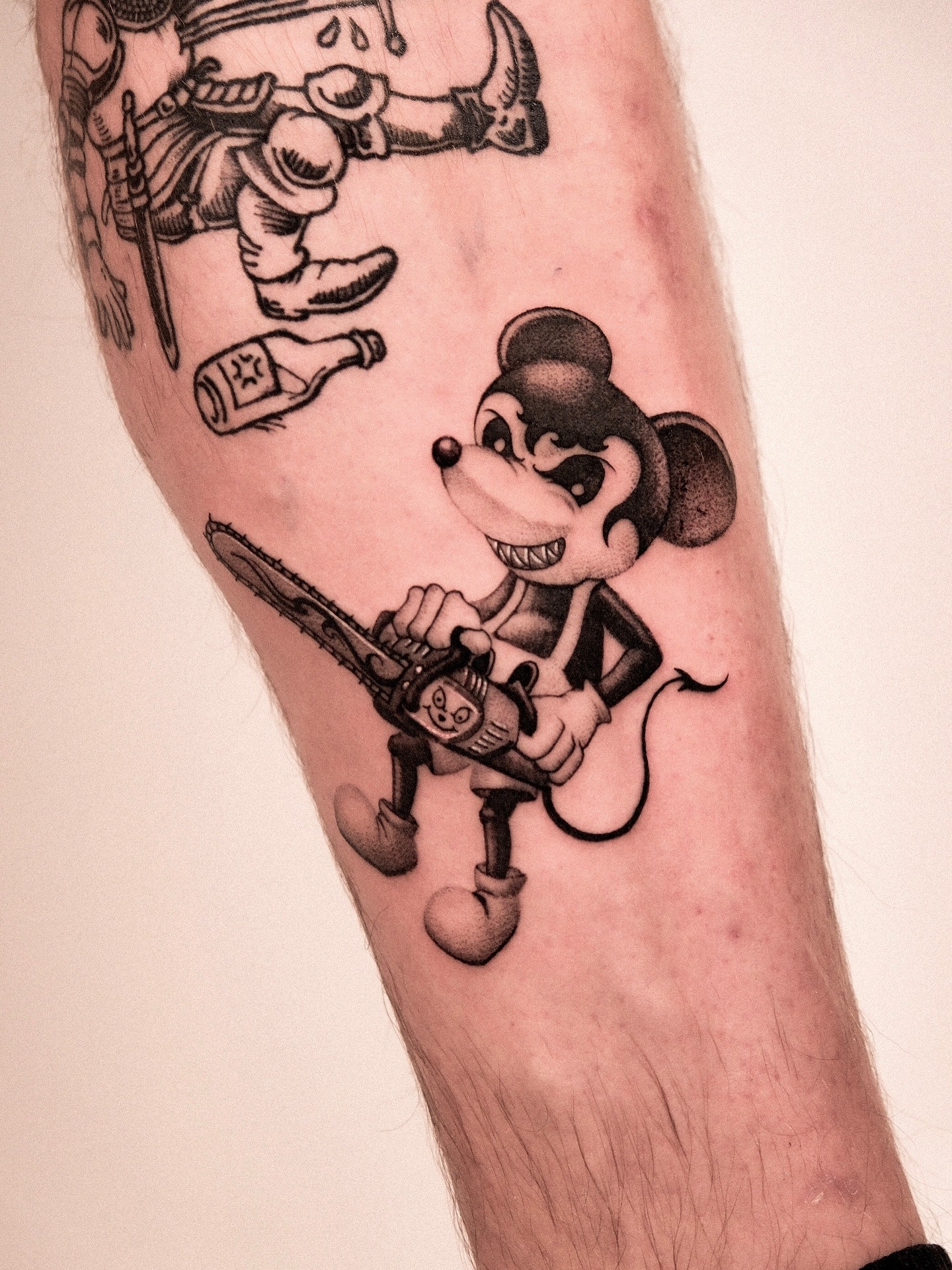 This tattoo features a playful yet edgy depiction of Mickey Mouse wielding a chainsaw.