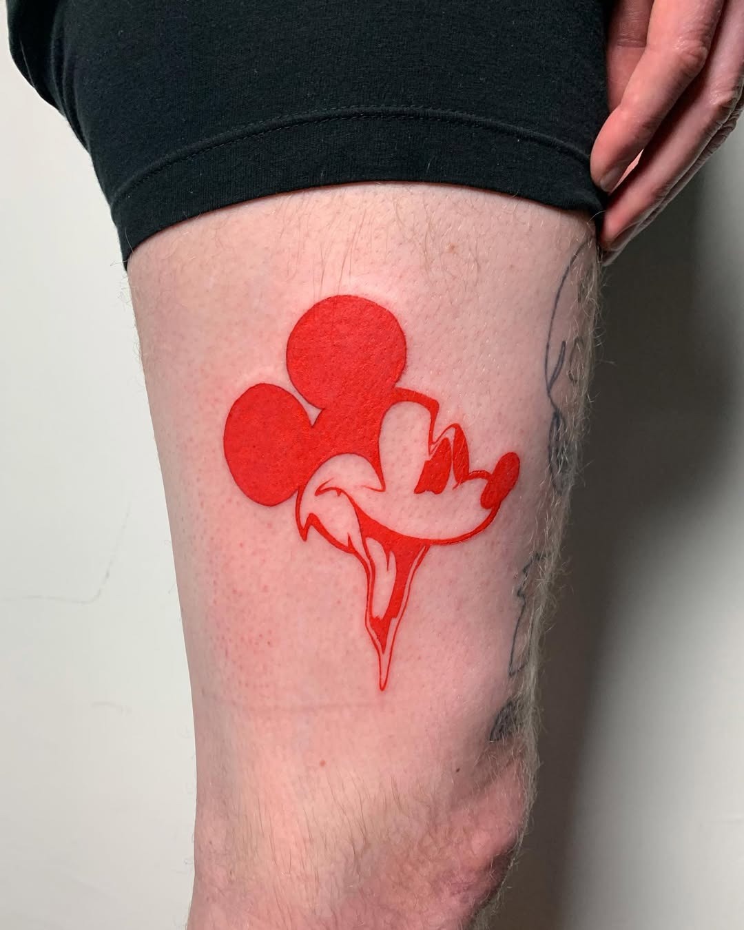 This striking tattoo features Mickey Mouse in bold red, creating a playful vibe.