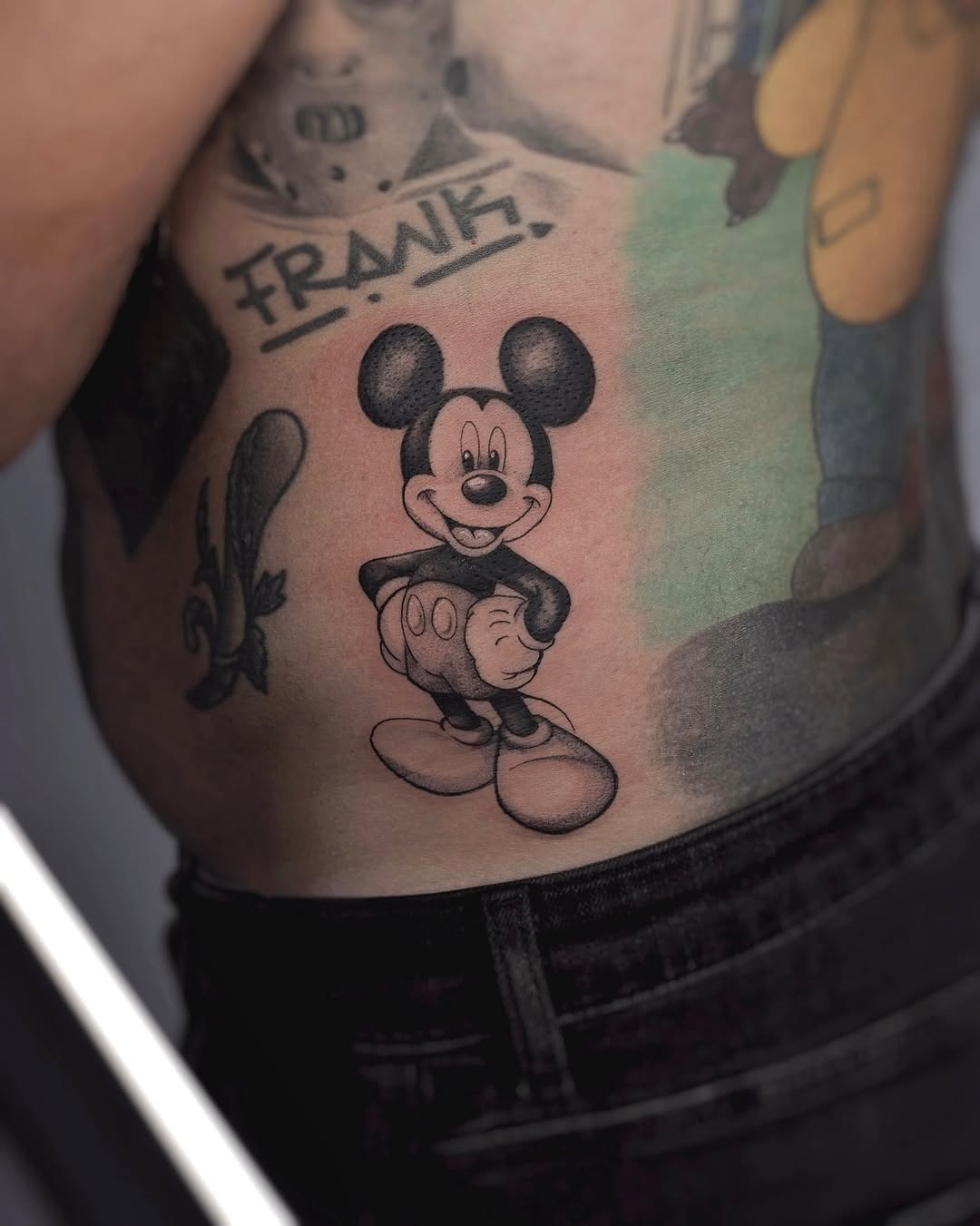 This tattoo features a classic depiction of Mickey Mouse in black ink.