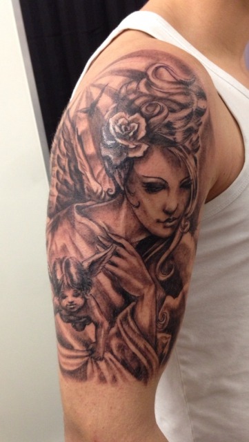 This tattoo features an ethereal depiction of an angel cradling a child, embodying a sense of divine protection and maternal love.