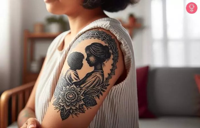 This tattoo uses a silhouette style to depict a mother holding her child, surrounded by a floral frame.