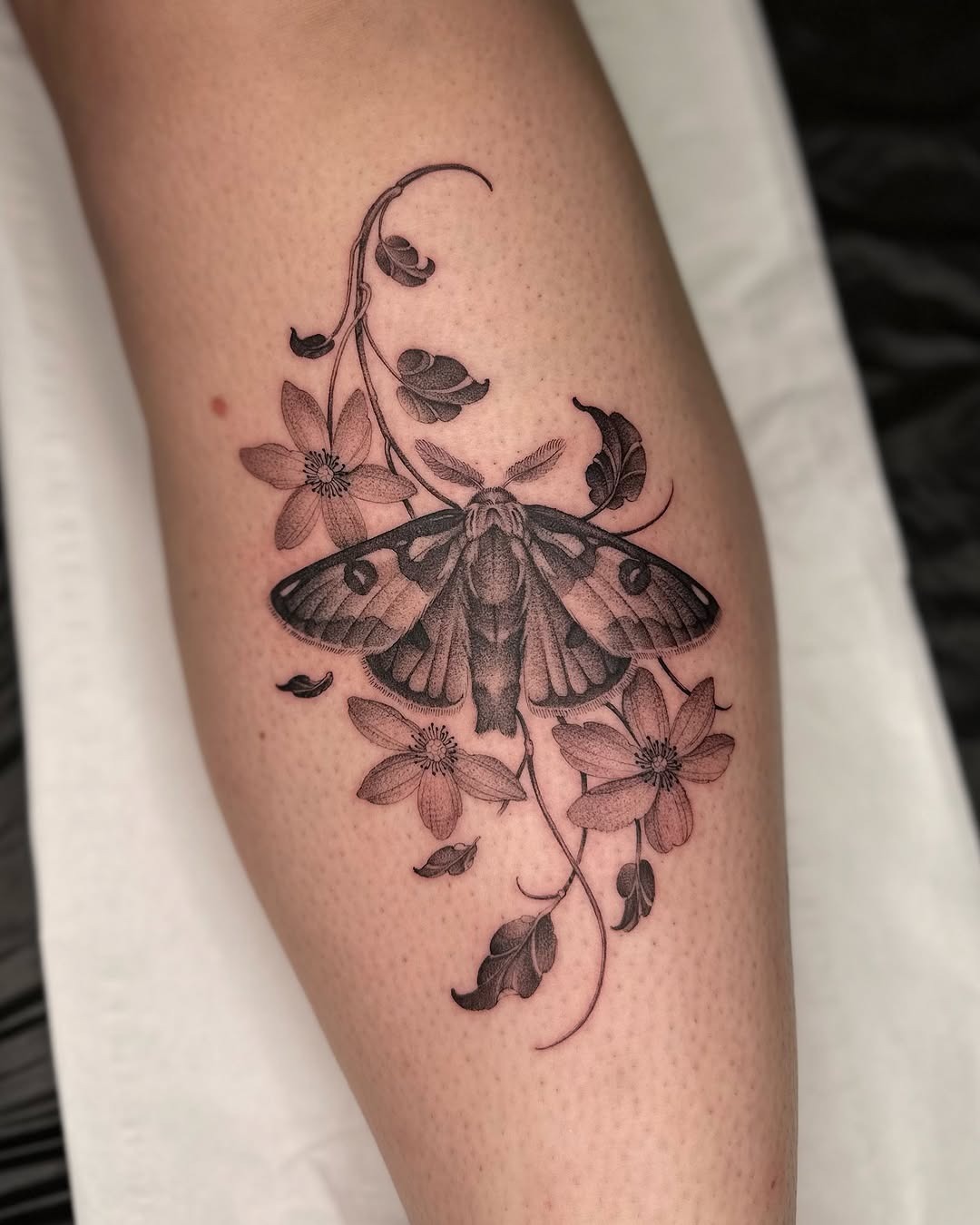 Intricate moth tattoo surrounded by floral elements Tattoo Design