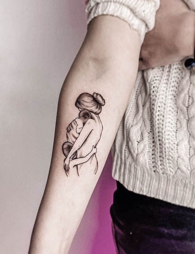 A Mother Kissing Her Baby Surrounded by Floral Elements Tattoo Design