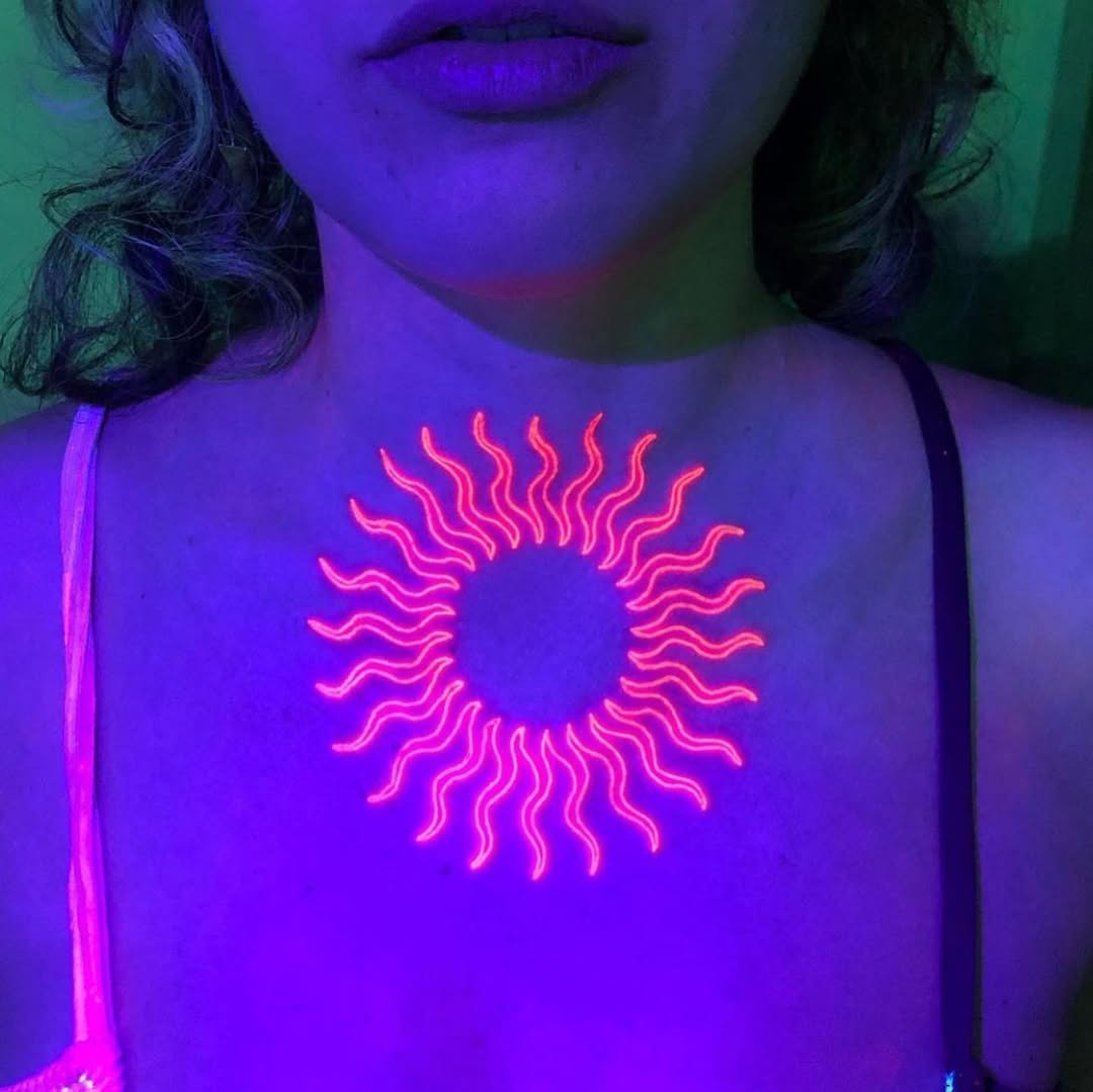 Vibrant neon sun tattoo glowing on chest Tattoo Design