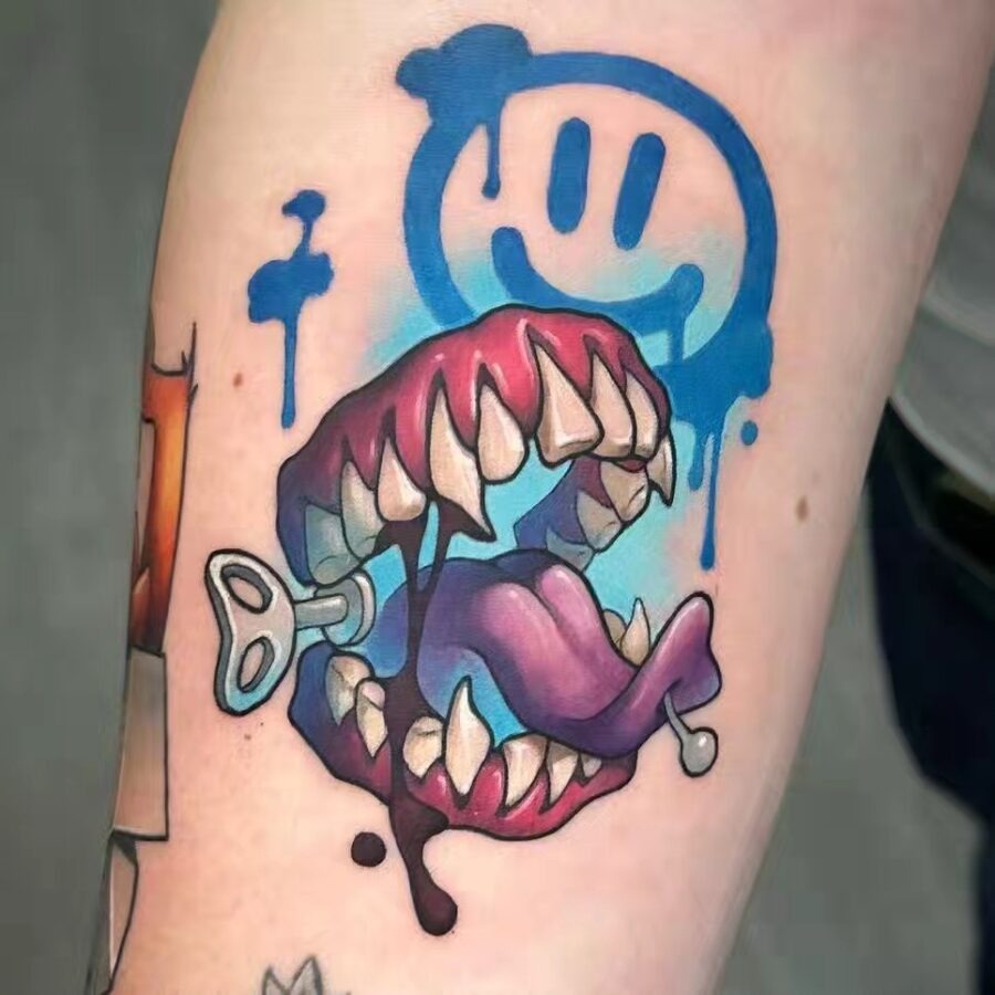 This tattoo features a, cartoonish mouth with exaggerated teeth and a playful tongue.