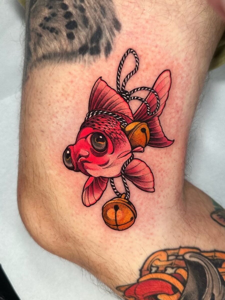 This tattoo showcases a goldfish accompanied by whimsical bells.