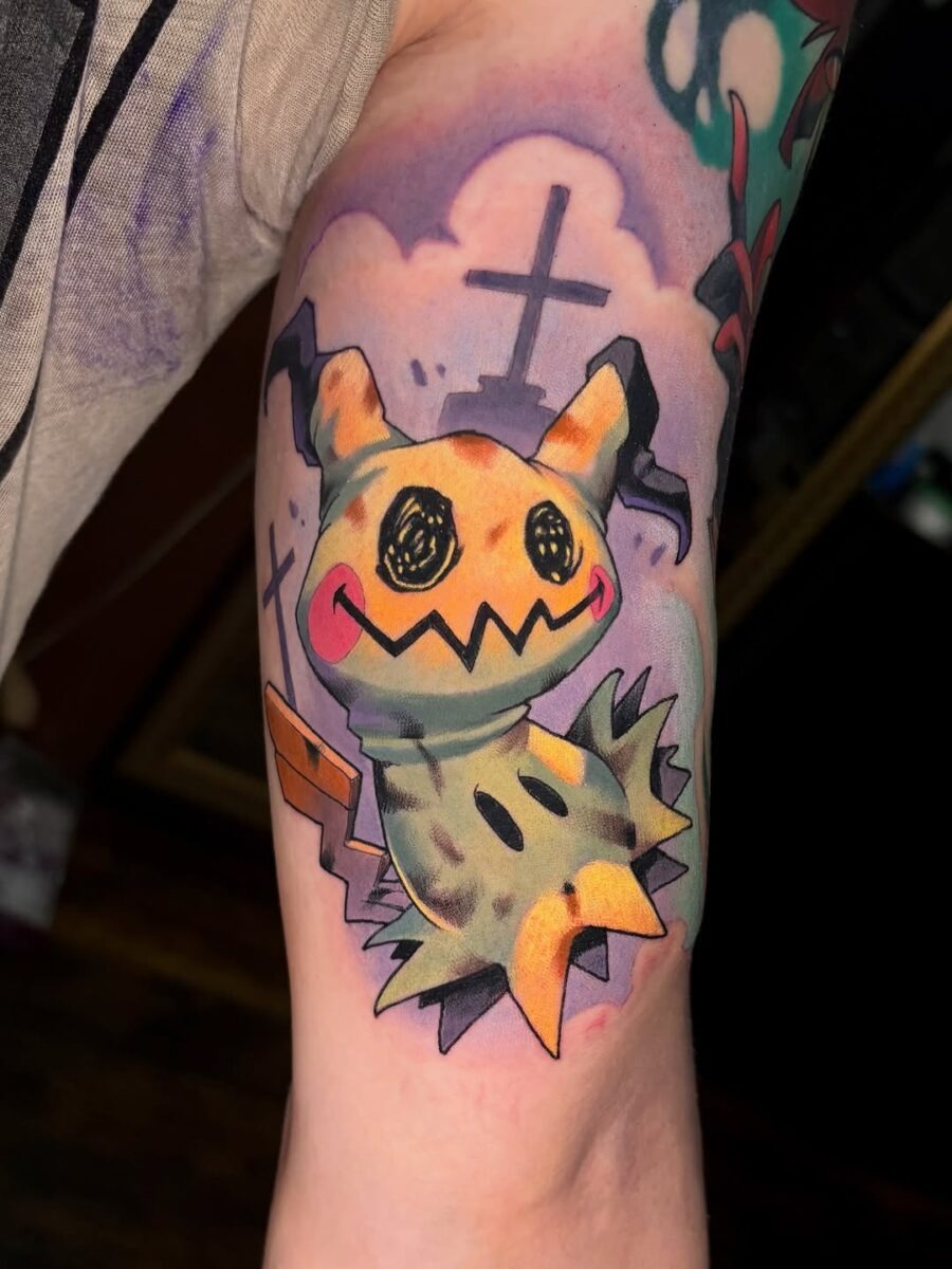 This Mimikyu tattoo showcases a fun and playful character, adorned with bright colors and a mischievous smile.