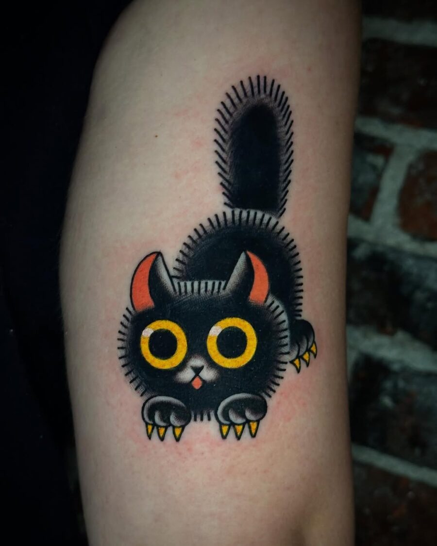This tattoo features a playful black cat, showing bold colors and cartoonish style.