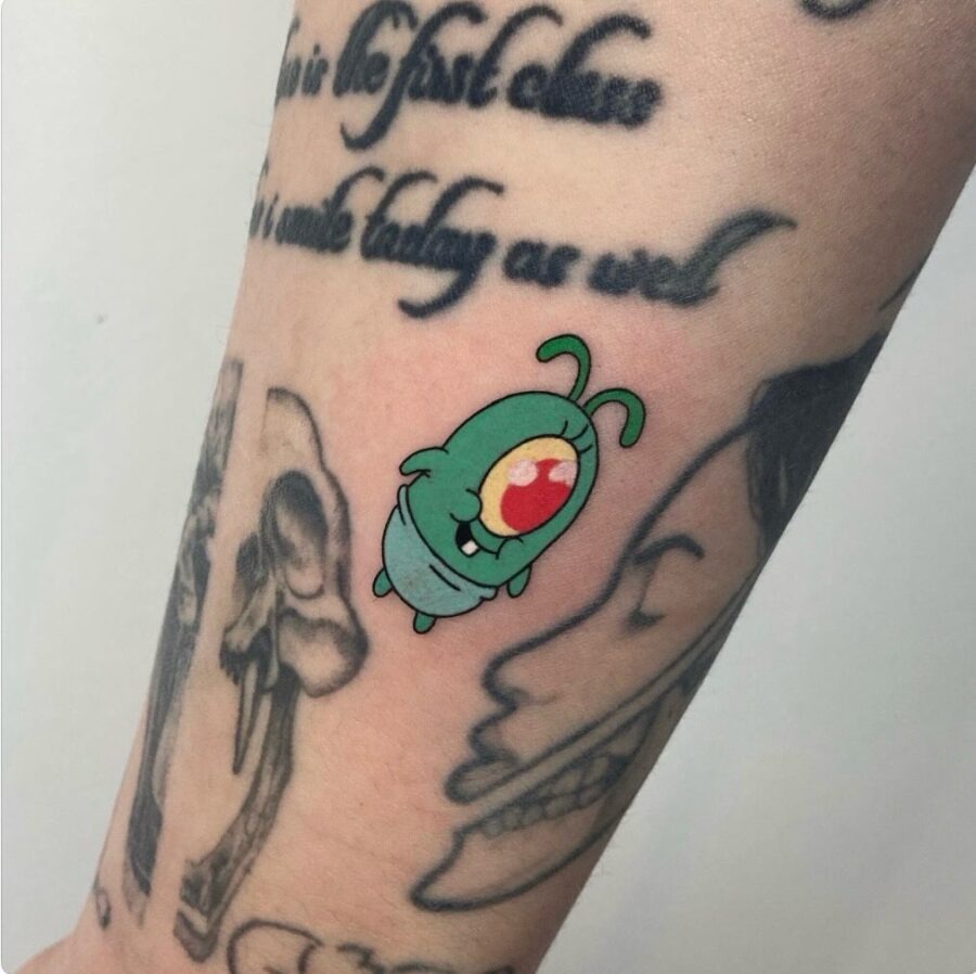 This tattoo features a whimsical cartoon character in bright green hues.