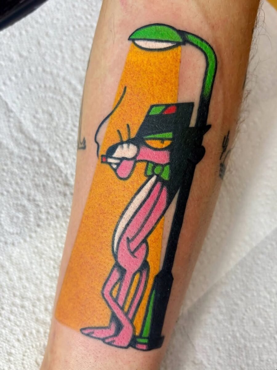 This tattoo features the iconic Pink Panther leaning against a street lamp, exuding a fun, retro vibe.