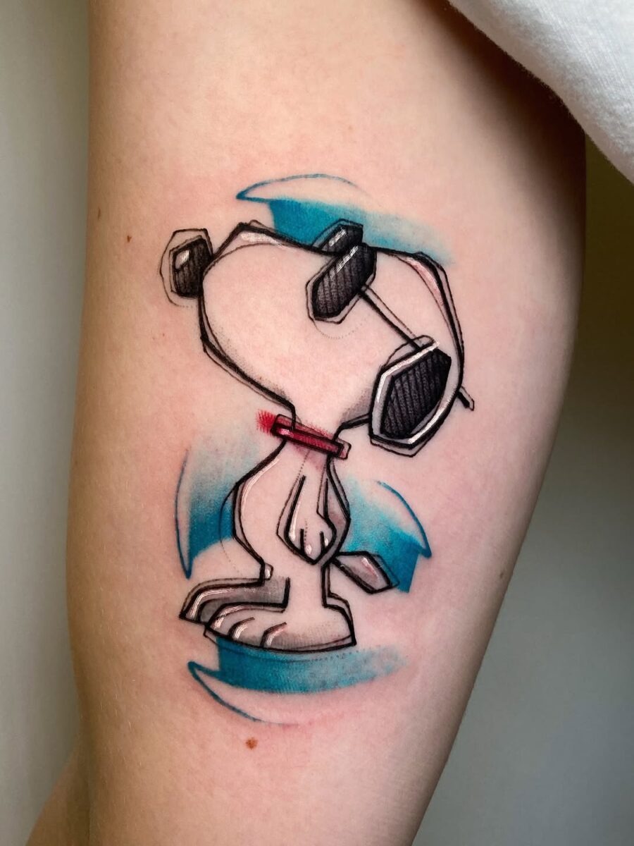 This tattoo features a, cartoonish Snoopy with a whimsical design.