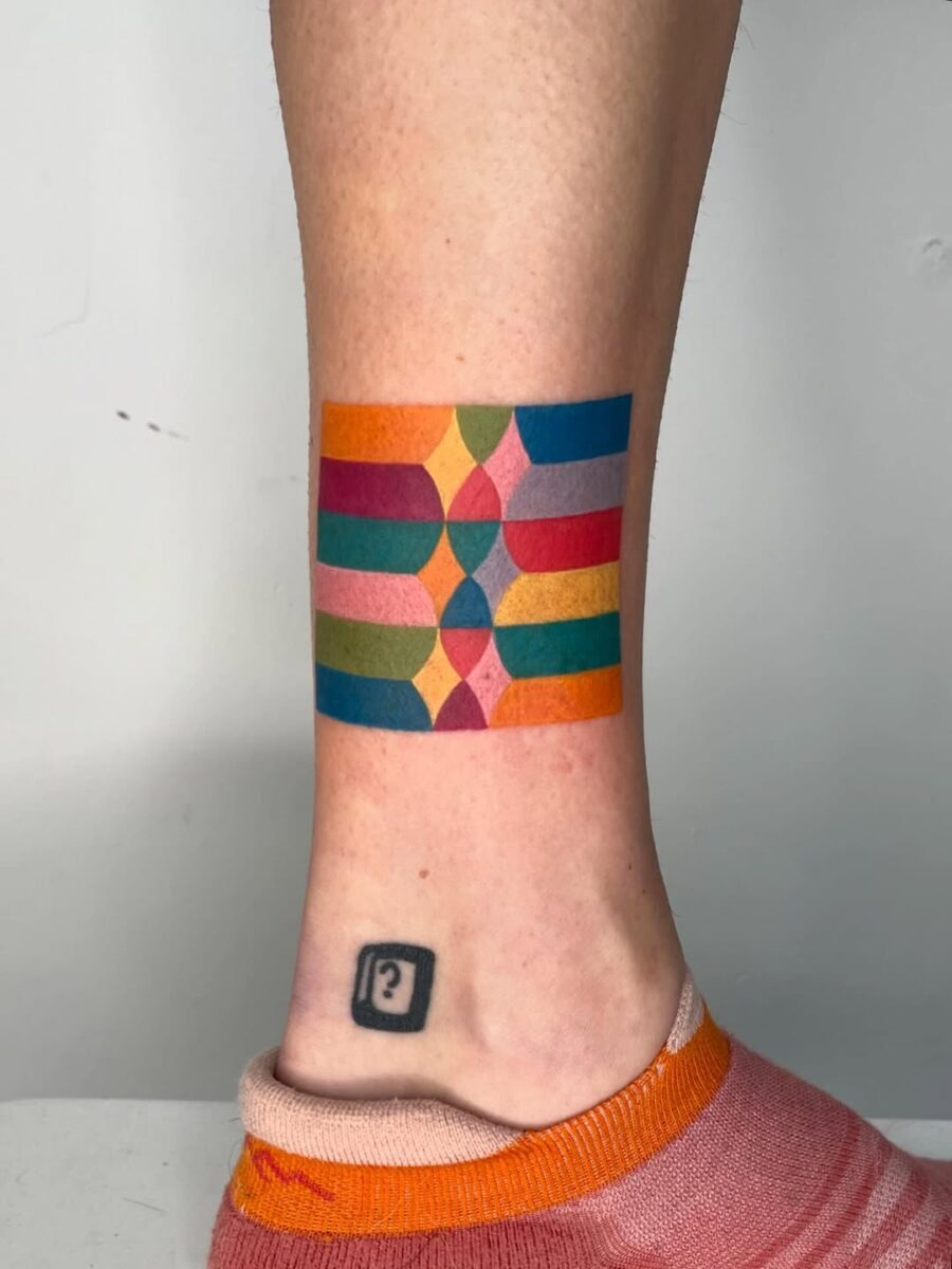 This unique tattoo features a blend of bold geometric shapes and colors, offering a playful and modern aesthetic.