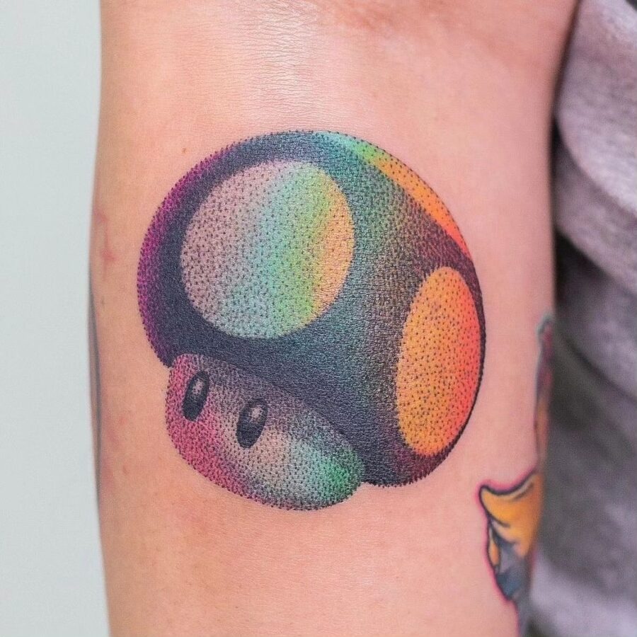 This tattoo showcases a colorful mushroom inspired by classic video games.