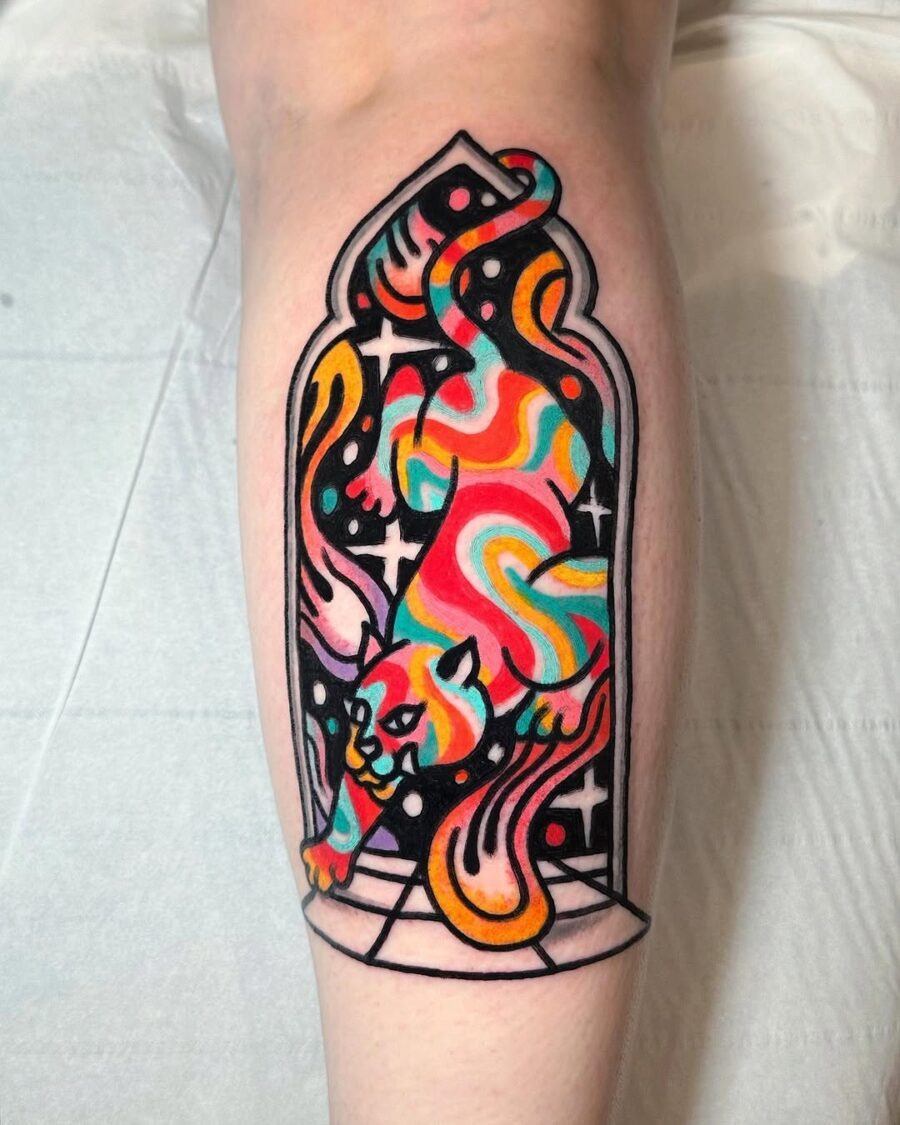 This tattoo features a vividly colored panther, bursting out of a stained glass frame.