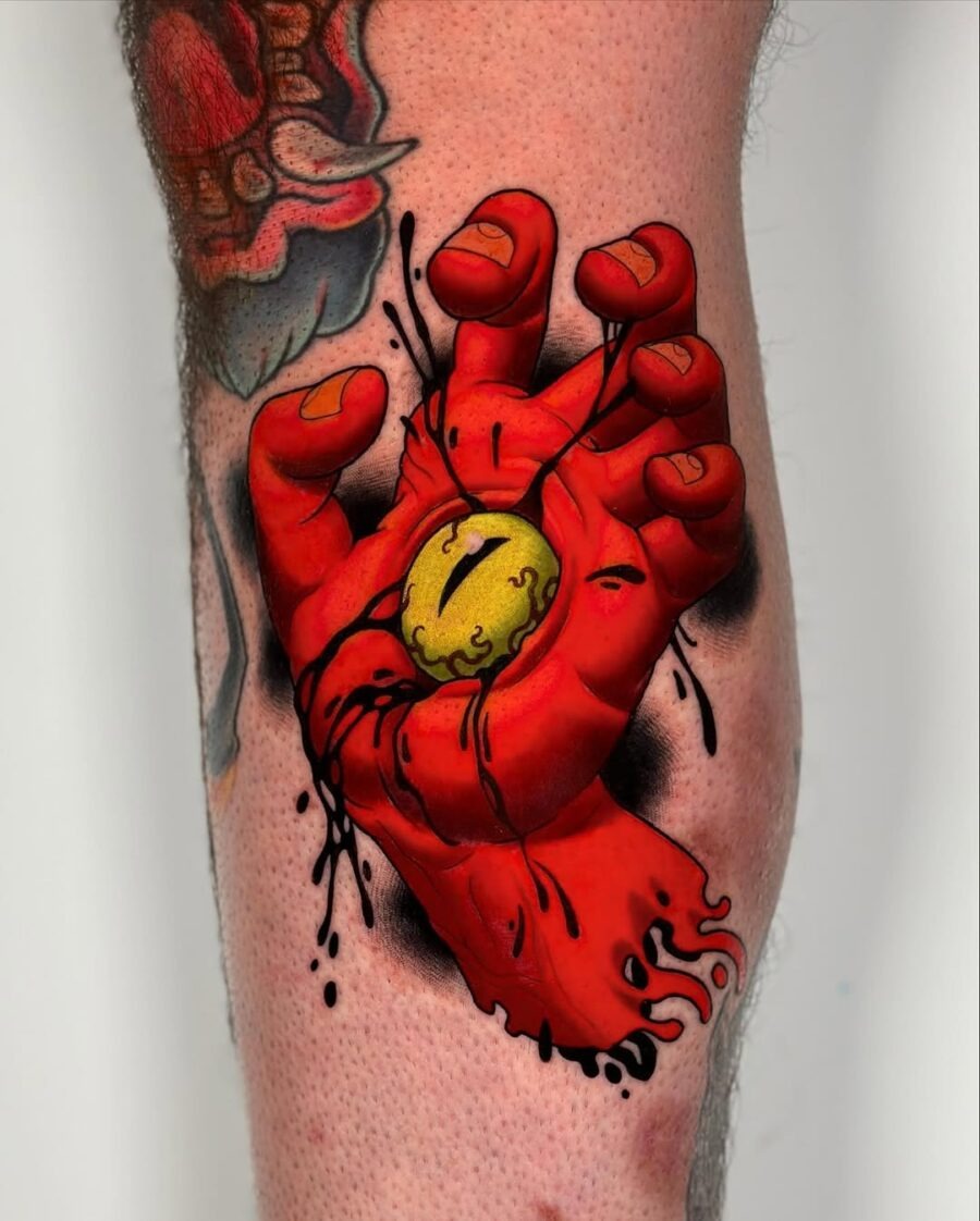 This tattoo showcases a striking red hand gripping a pulsating yellow orb.