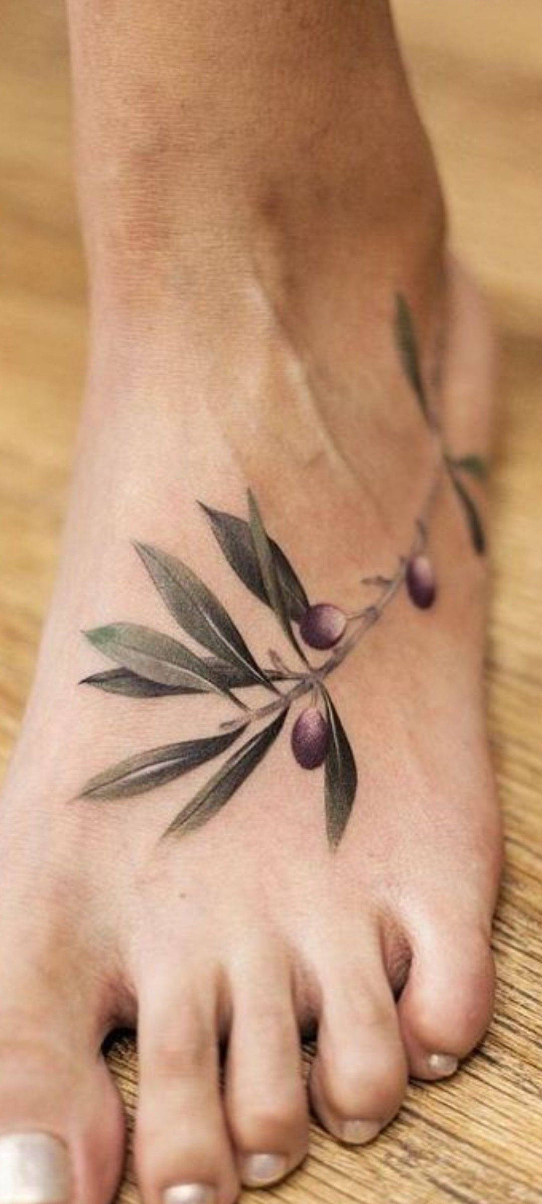 Delicate Olive Sprig Across the Foot, a tattoo design rendered in clean detailed linework for the ankle.