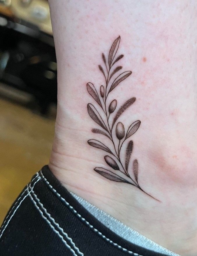 Tiny Olive Branch at the Ankle, a tattoo design rendered in delicate fine-line.