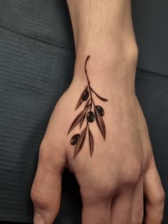 Tiny Olive Branch Tattoo on the Hand, a tattoo design rendered in delicate fine-line.