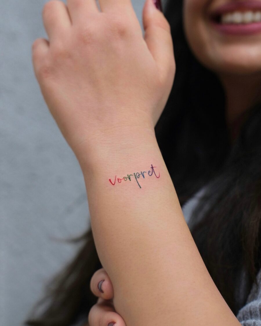 Colorful one-word tattoo on wrist Tattoo Design