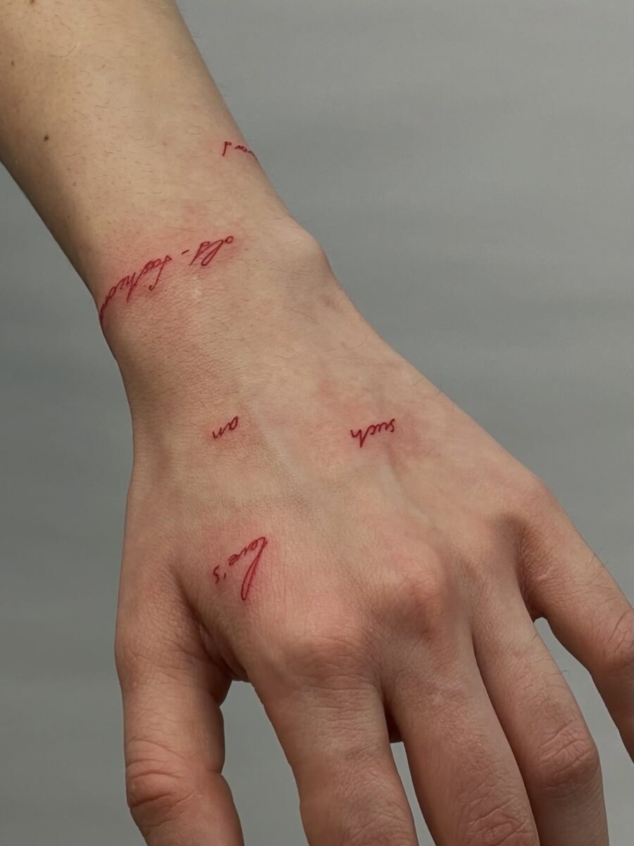 Elegant red script tattoos on the hand Tattoo Design