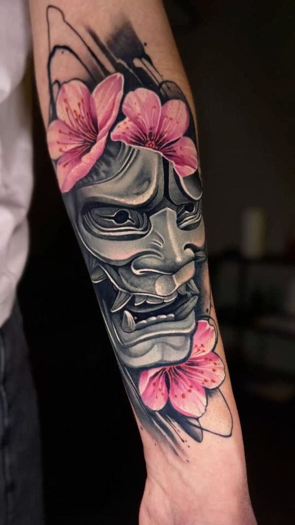 There's something hauntingly beautiful about this Japanese oni tattoo done in realistic grey tones, surrounded by bright, painterly cherry blossoms.