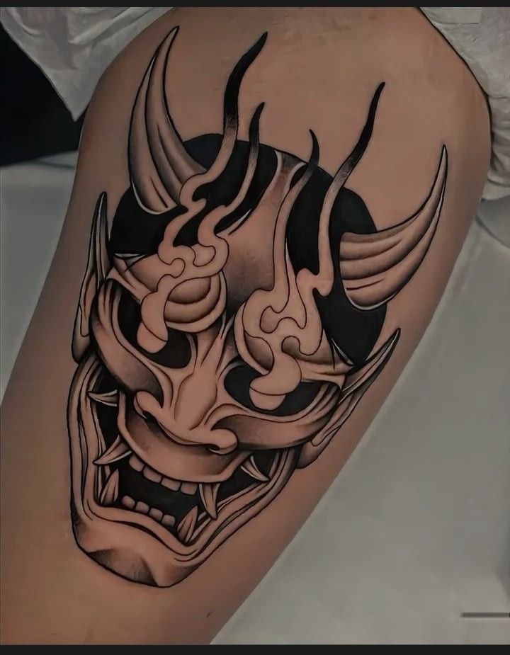 Smooth, sculptural, and almost 3D in its blackwork, this oni mask seems carved into the thigh.