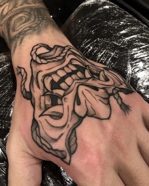 A torn mask tattooed on the hand, this piece explores the idea of masks we wear, and when they fall away.