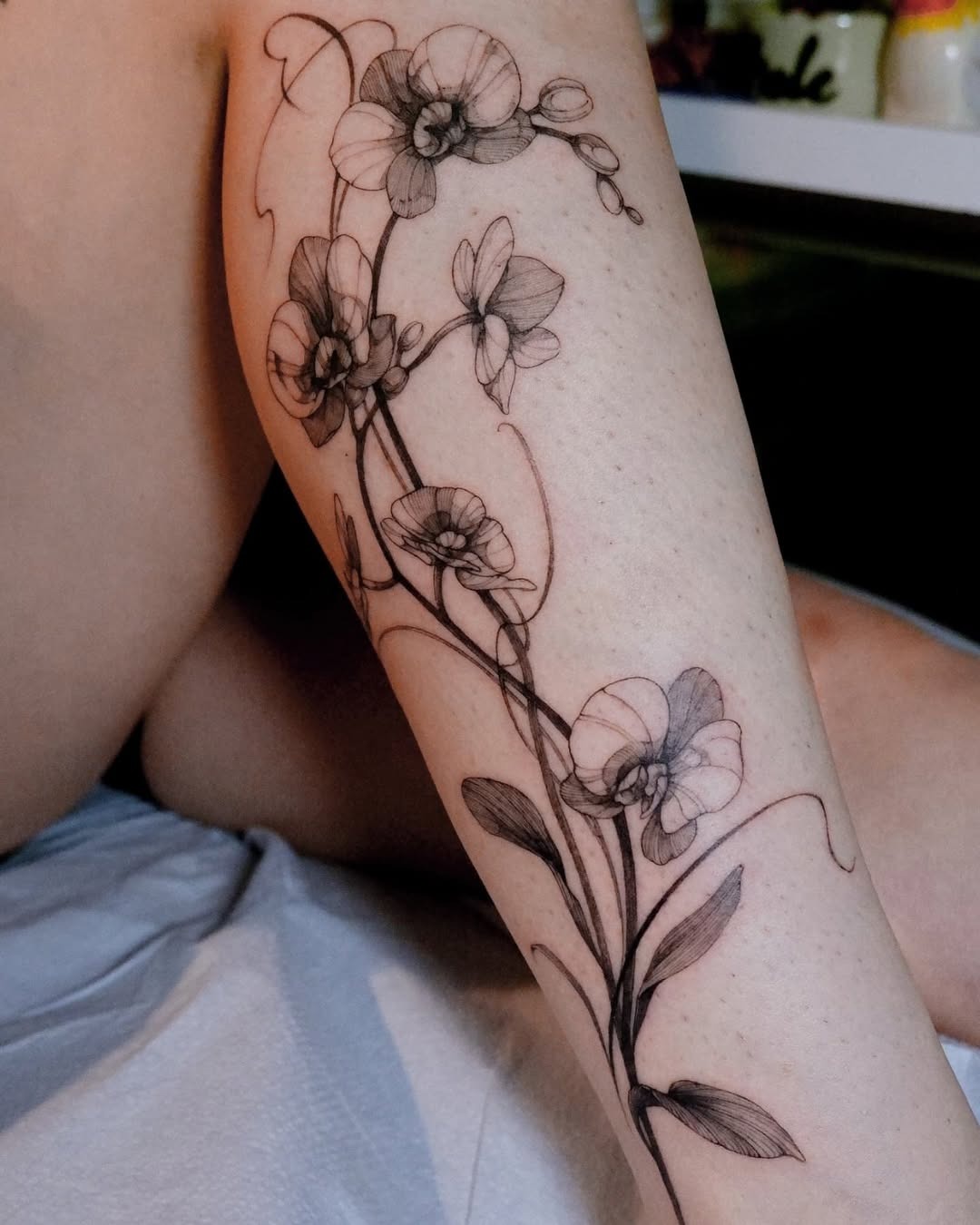 Elegant orchid tattoo wrapping around the leg Tattoo Design