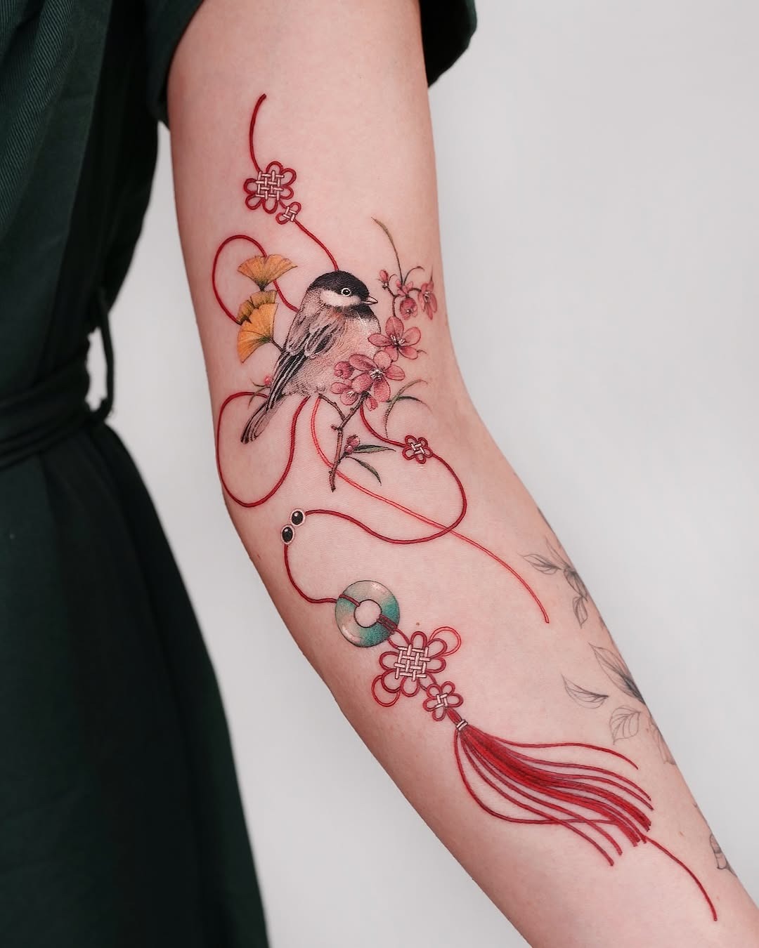 Elegant bird surrounded by floral elements and ribbons Tattoo Design