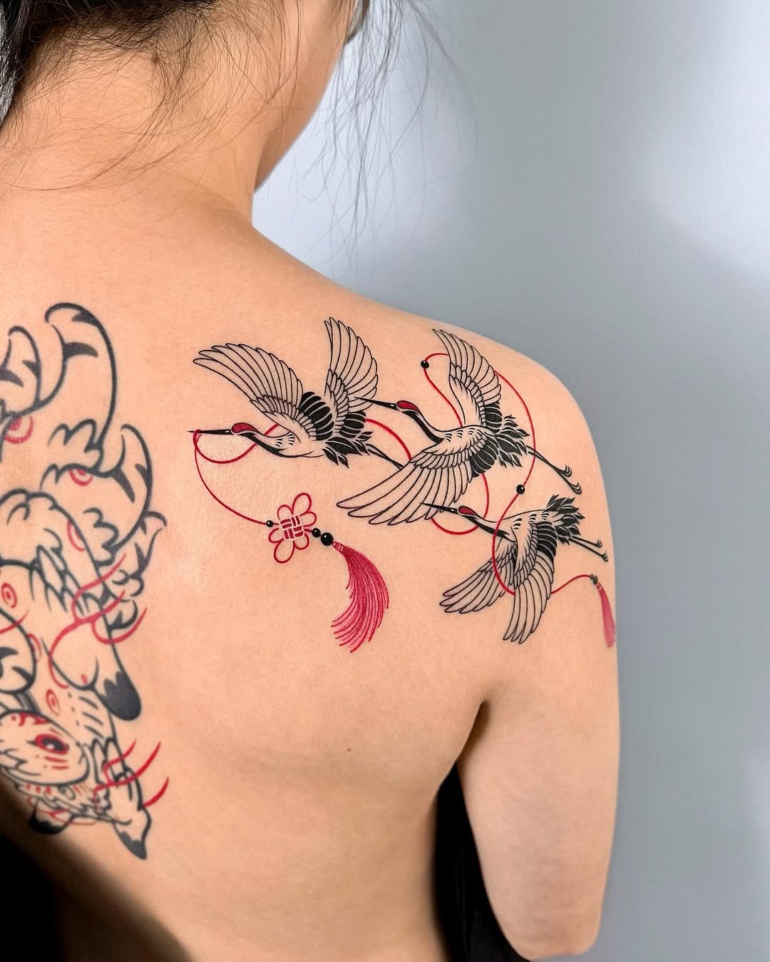 Elegant cranes intertwined with red threads Tattoo Design