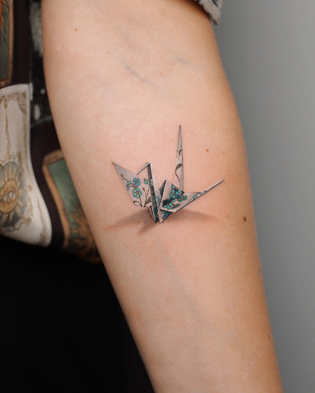 Elegant origami crane tattoo with floral details Tattoo Design