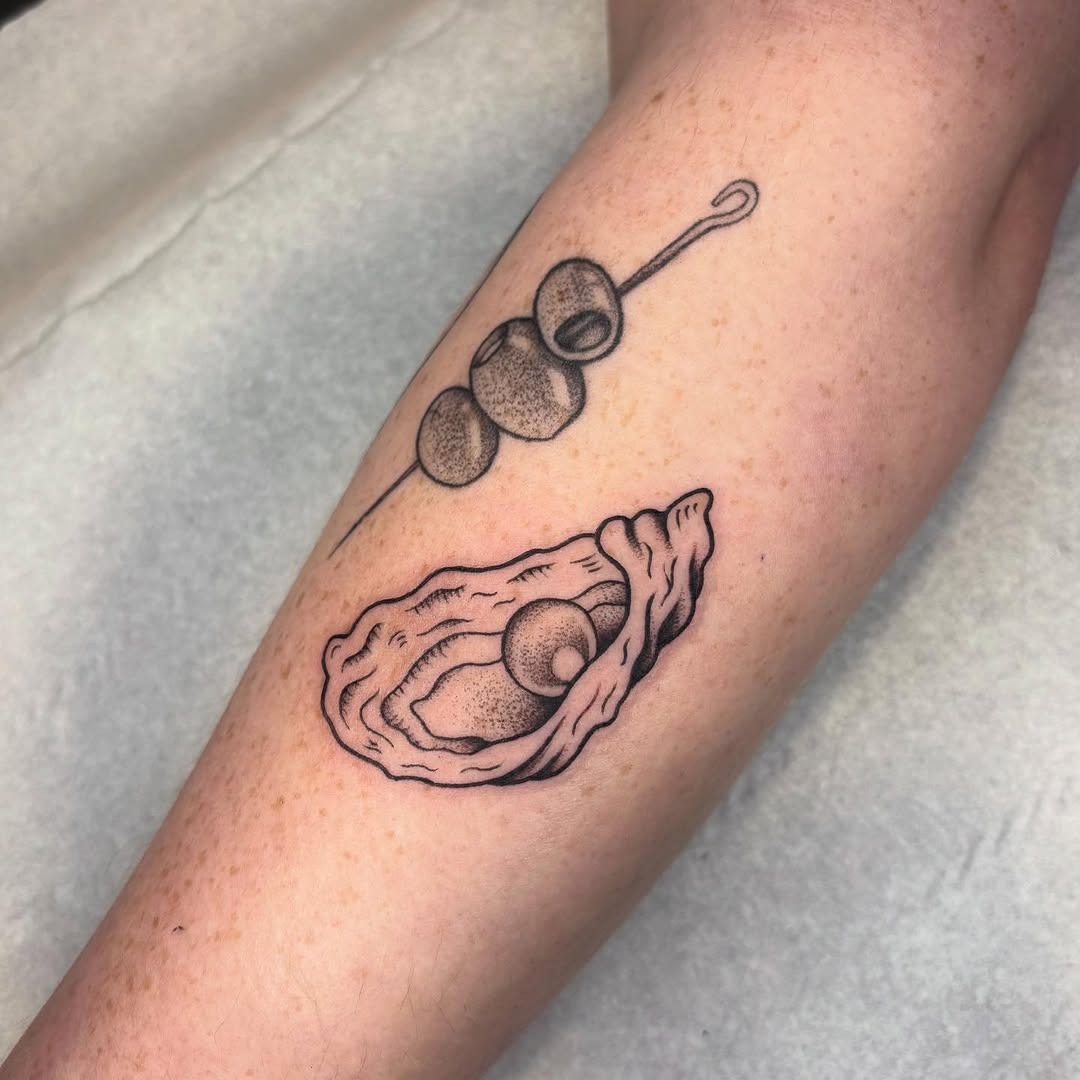 This tattoo features a beautifully detailed oyster with a pearl nestled inside, emphasizing nature's elegance.