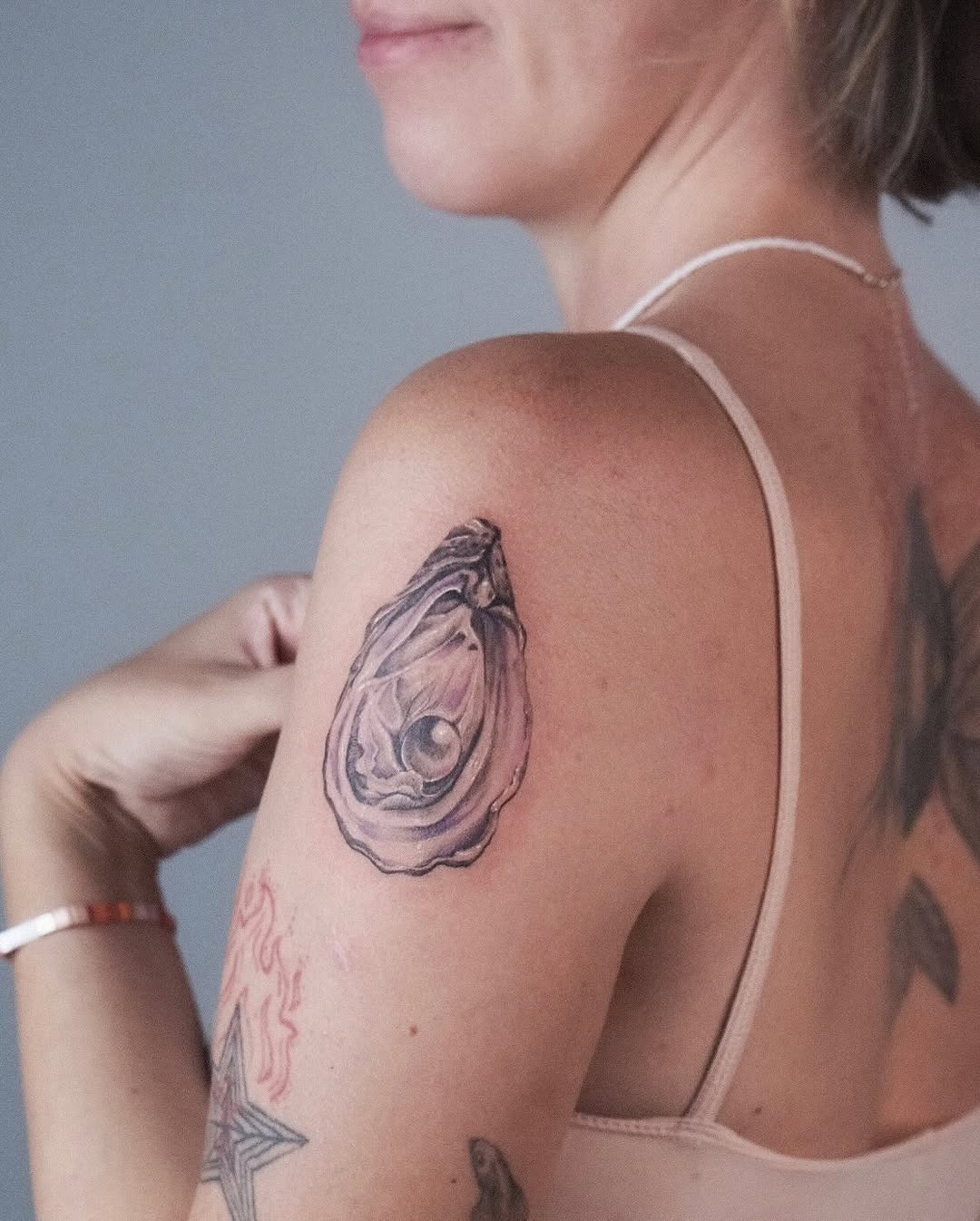 This tattoo showcases a beautifully detailed oyster with a pearl nestled inside.