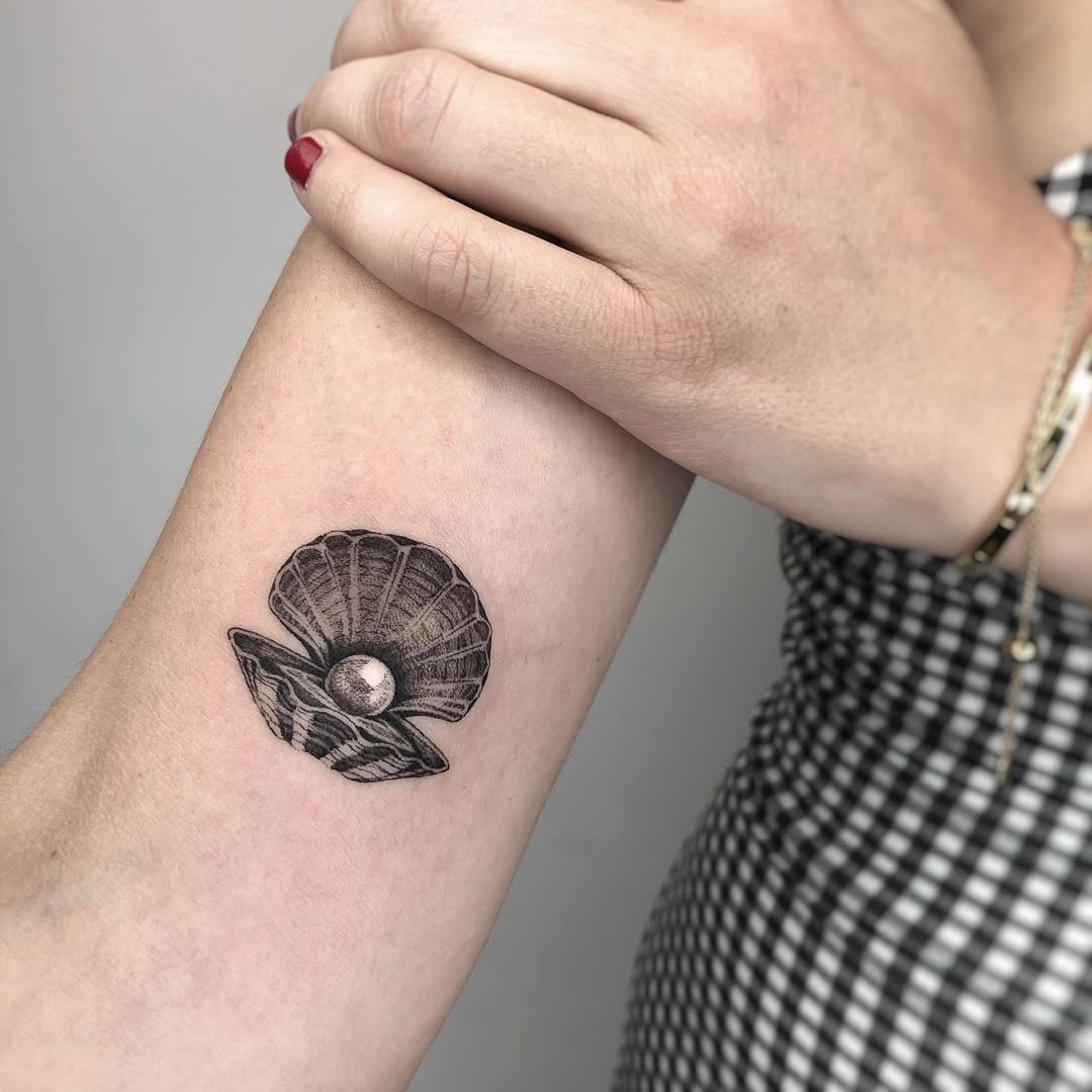 This tattoo showcases a beautifully detailed oyster shell, elegantly opened to reveal a lustrous pearl inside.