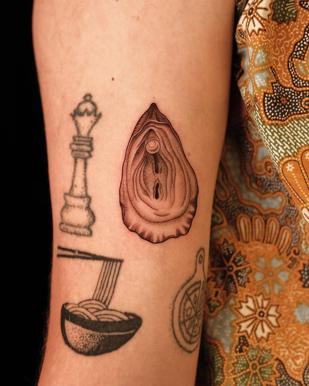 This tattoo showcases a beautifully detailed oyster, capturing its intricate texture and natural beauty.