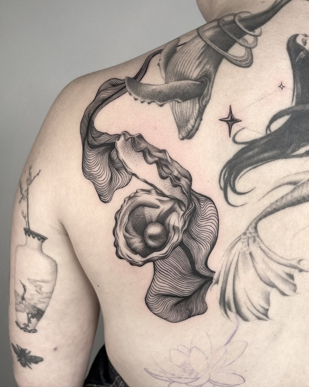 This striking oyster tattoo features intricate line work and a beautifully rendered pearl inside.