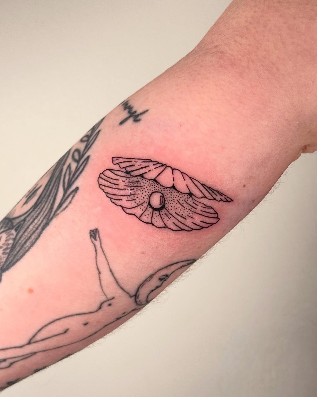 This detailed oyster tattoo showcases fine line artistry with an elegant and minimalist style.