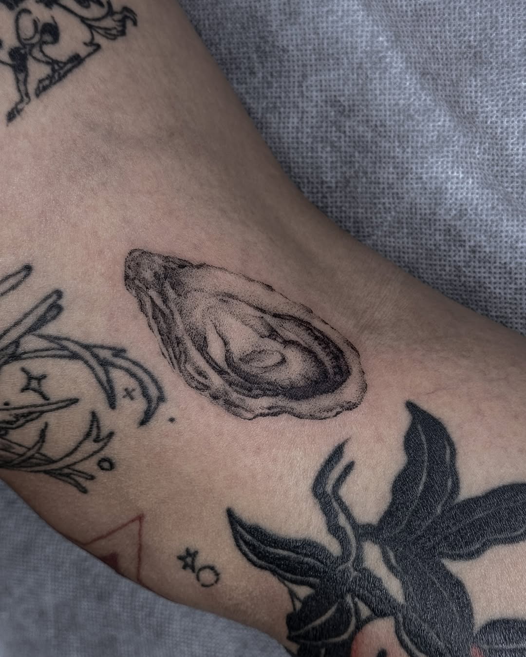 This tattoo showcases a beautifully detailed oyster, prominently displayed on the forearm.