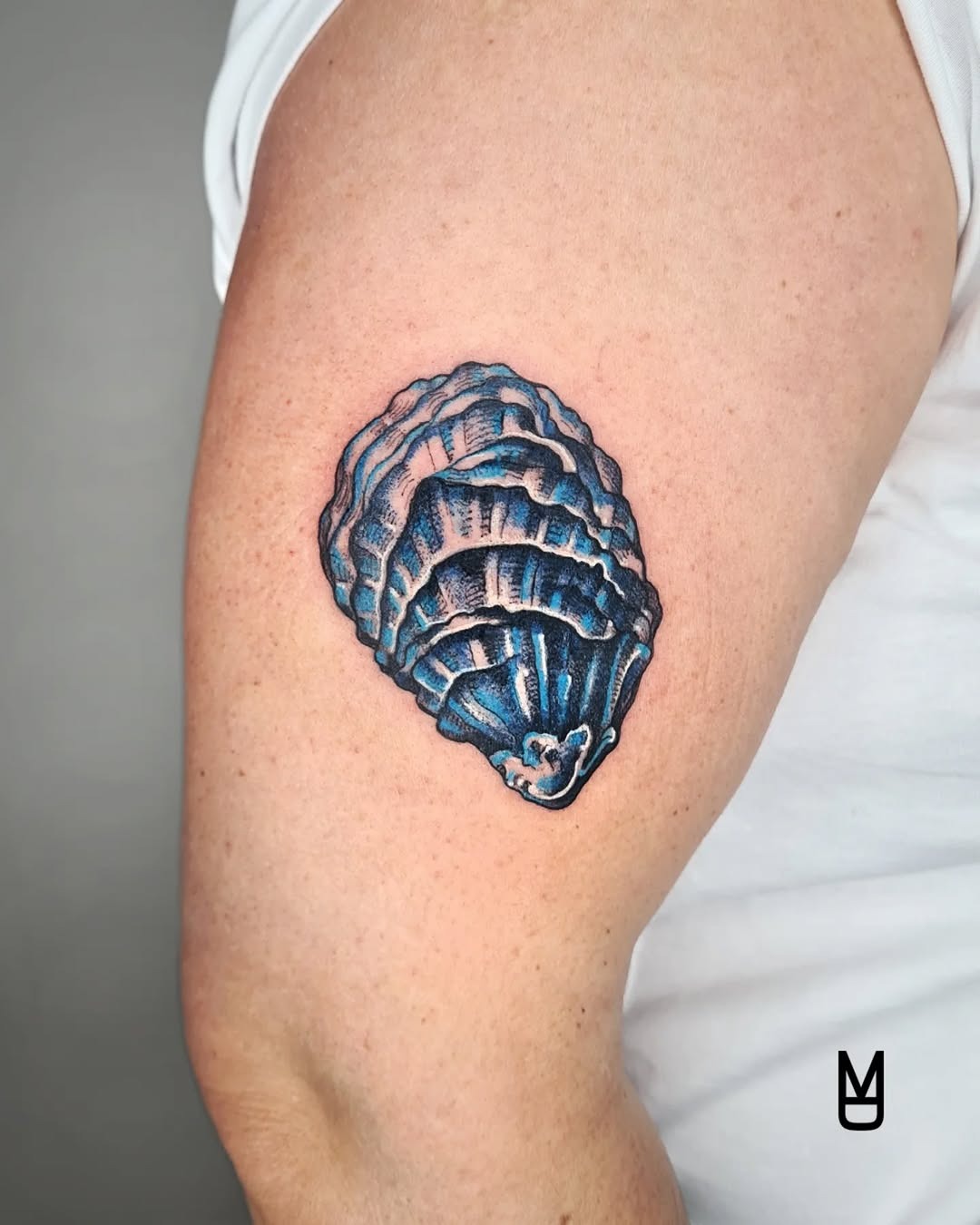 This beautiful oyster tattoo showcases intricate details and a striking use of blue ink.