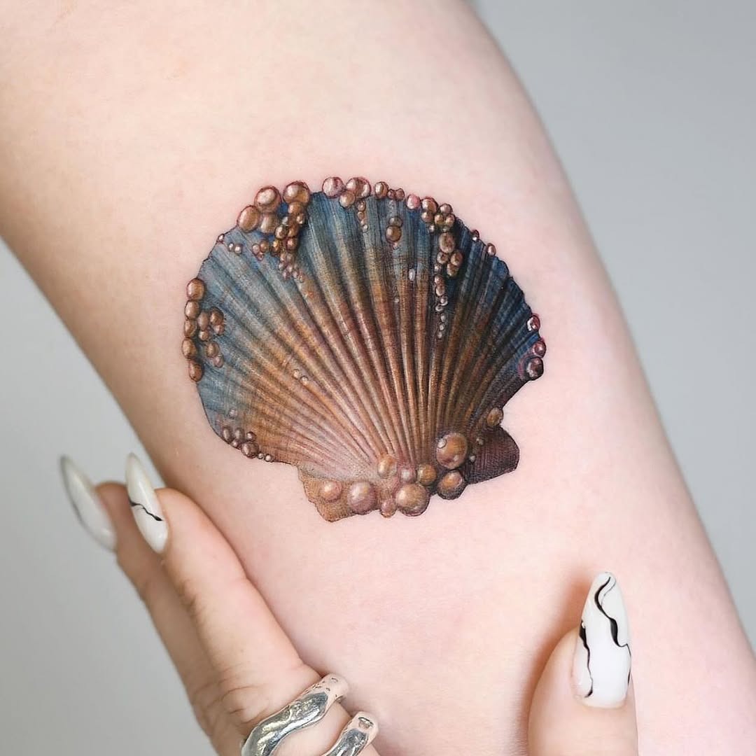 This tattoo showcases a beautifully detailed oyster shell, complete with shimmering bubbles.