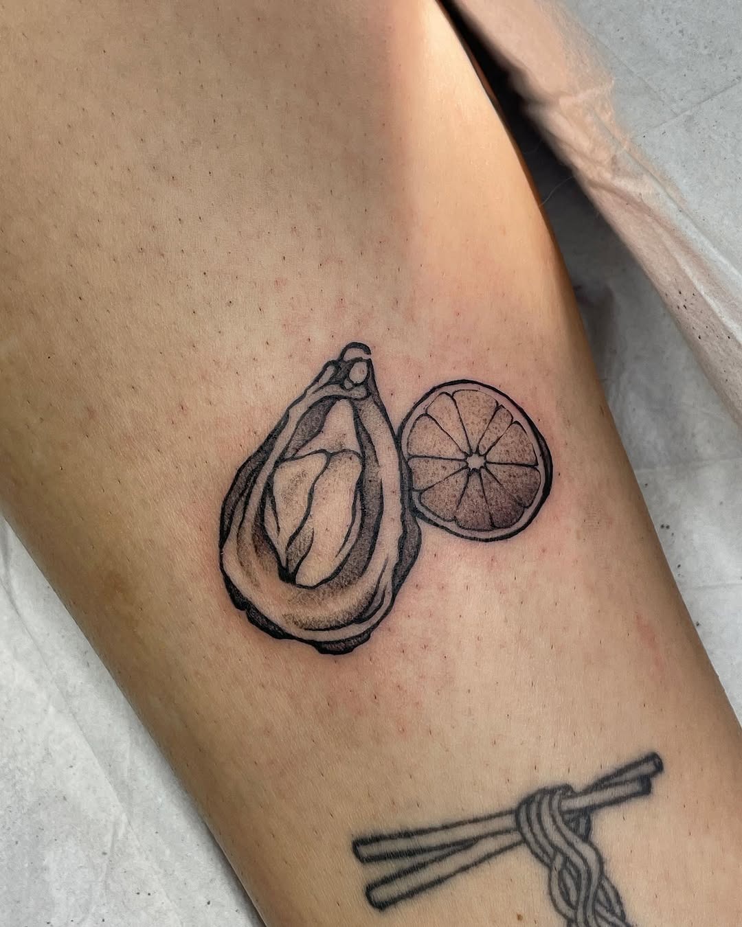 This tattoo showcases a beautifully detailed oyster paired with a lemon slice.